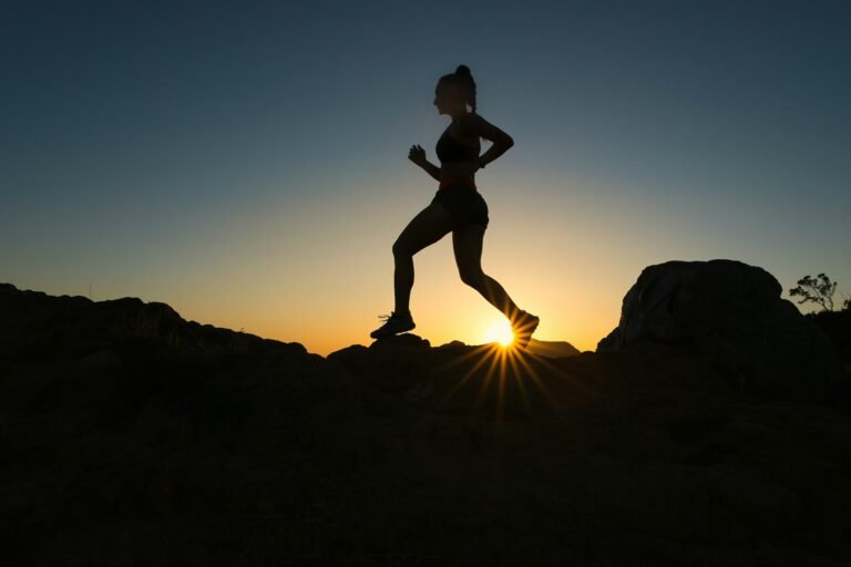 A runner in silhouette on a rocky trail