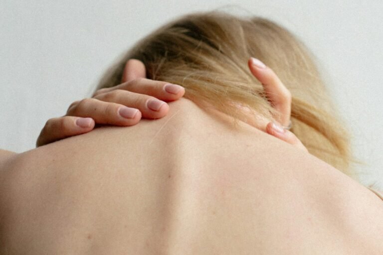 A person reaching for the back of their own neck